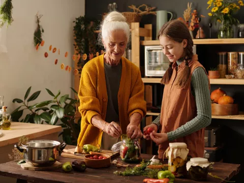 Grandmother and granddaughter cooking together in a kitchen.