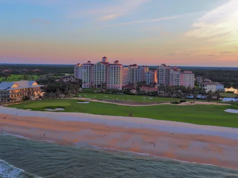 A sunset, tropical scene of a hotel resort next to the beach