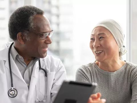 A doctor speaks with a patient undergoing cancer treatment. 