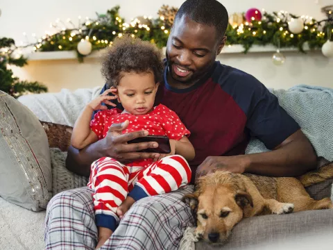 A father an son sit together on the couch during the holiday season. 