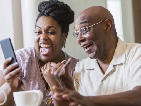 A couple laughing on a video call.
