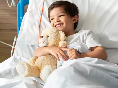 A little boy hugs his teddy bear while in the hospital.