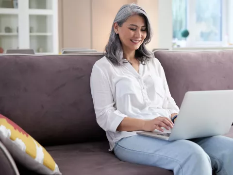 A woman using her computer while sitting on the couch.