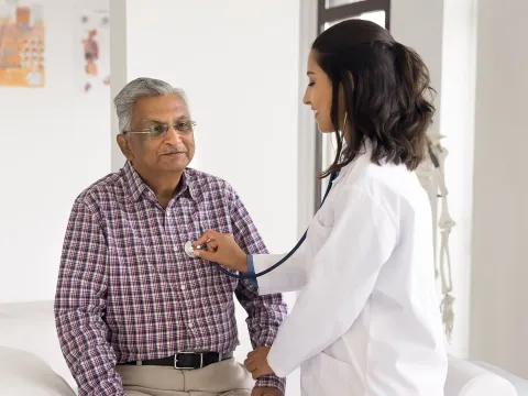 Female doctor checking the heart rate of a male patient.