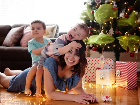 Caucasian mother with two sons laying under a Christmas tree.