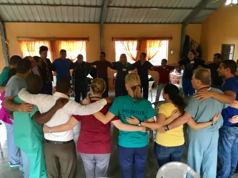 A group of physicians, nurses, and others in a group circle
