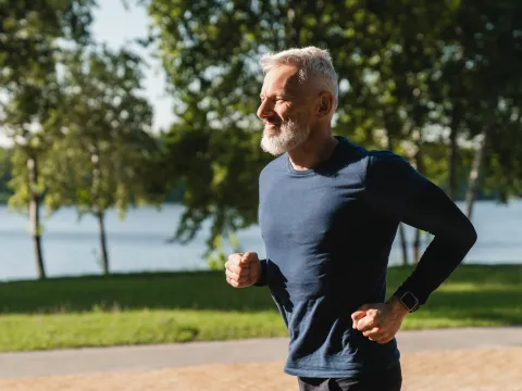 Senior Man Jogging in Park by Lake