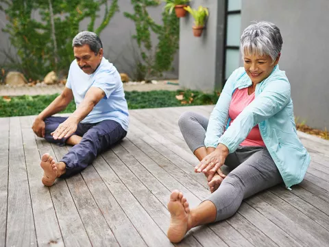 A couple doing leg stretches outdoors.