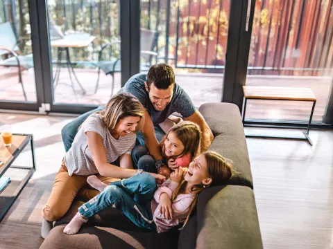 Parents playing with children at home in living room.