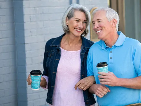 Older couple walking with coffee