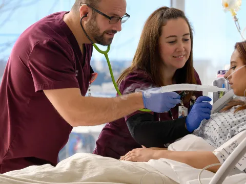 Nurses helping patient with medical equipment in emergency room.