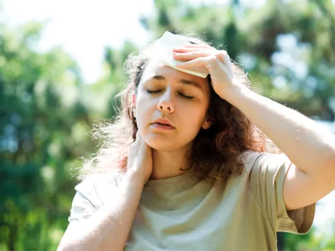 A woman wiping sweat from her brow while walking outdoors.