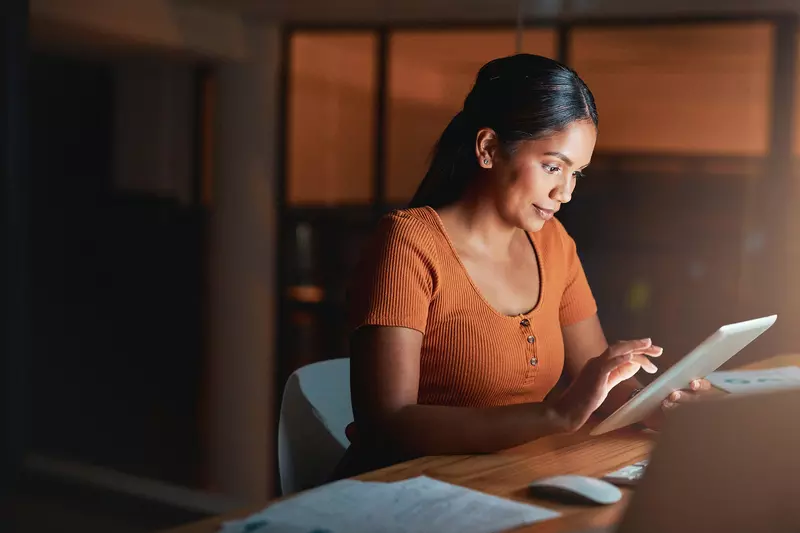 A Woman Surfs the Internet on a Table in a Dark Room of Her Home.