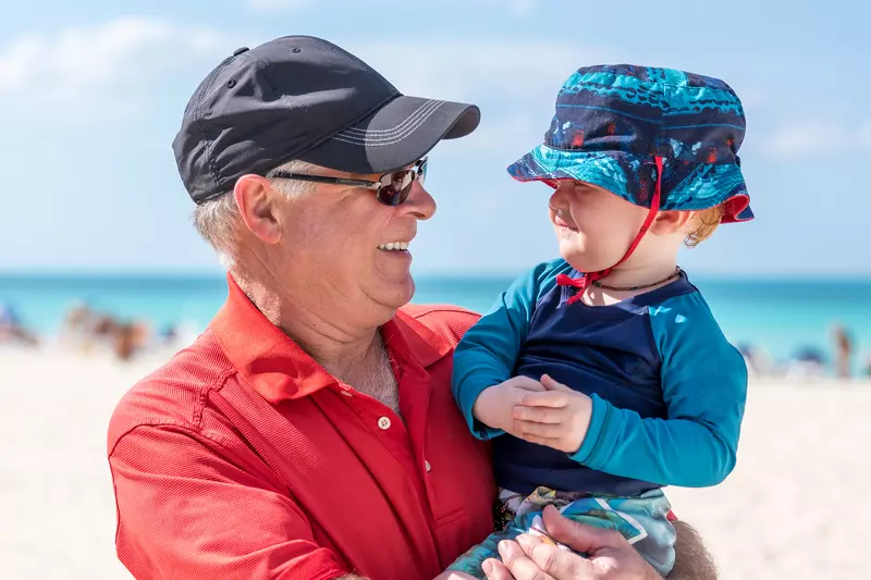 A Grandfather Holds His Grandson on the Beach