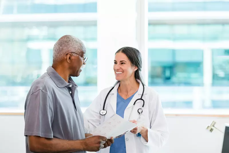 A Physician Smiles While She Goes Over a Patient's Chart With Him