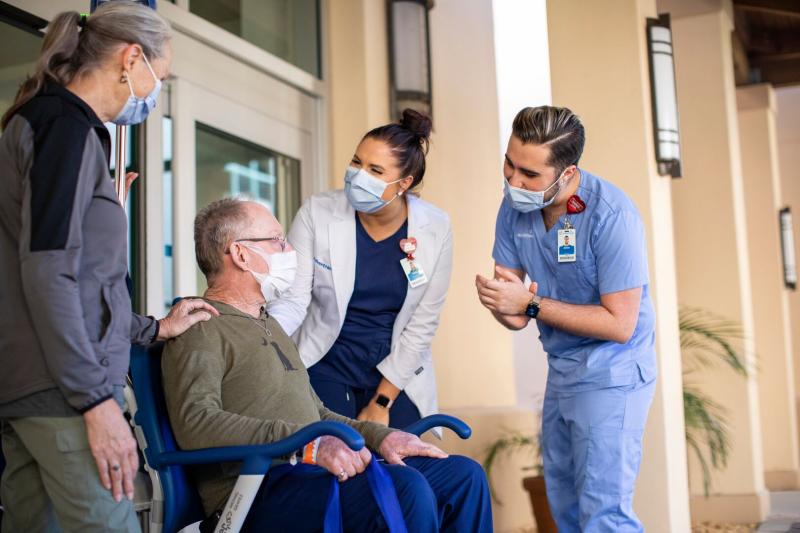 Nurses Helping Patient in Wheelchair Just Outside of the Hospital