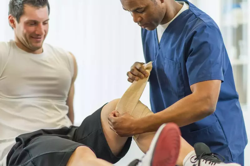 Physical Therapist Bandaging Patient's Knee