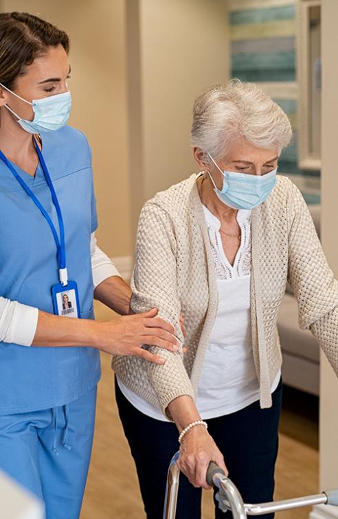 A Nurse Helps an Elderly Patient Navigate the Hallway of the Facility.