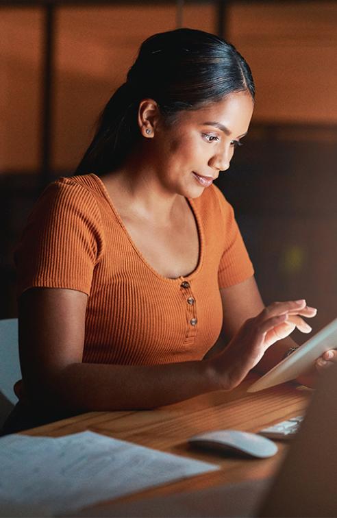 A Woman Surfs the Internet on a Table in a Dark Room of Her Home.