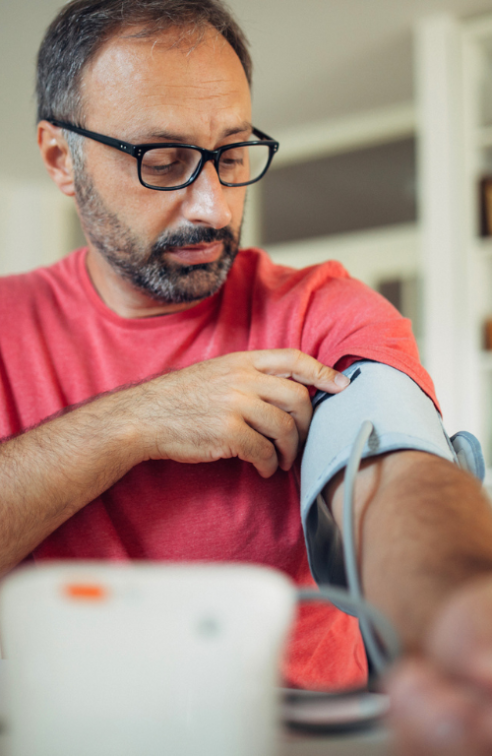 A Man Puts a Blood Pressure Cuff on His Arm in His Home.