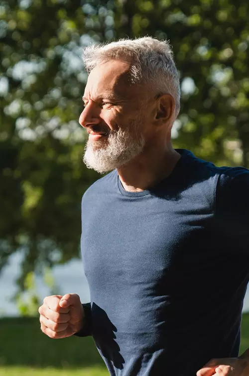 Senior Man Jogging in Park by Lake